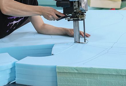 Foam being cut and shaped for upholstered furniture
